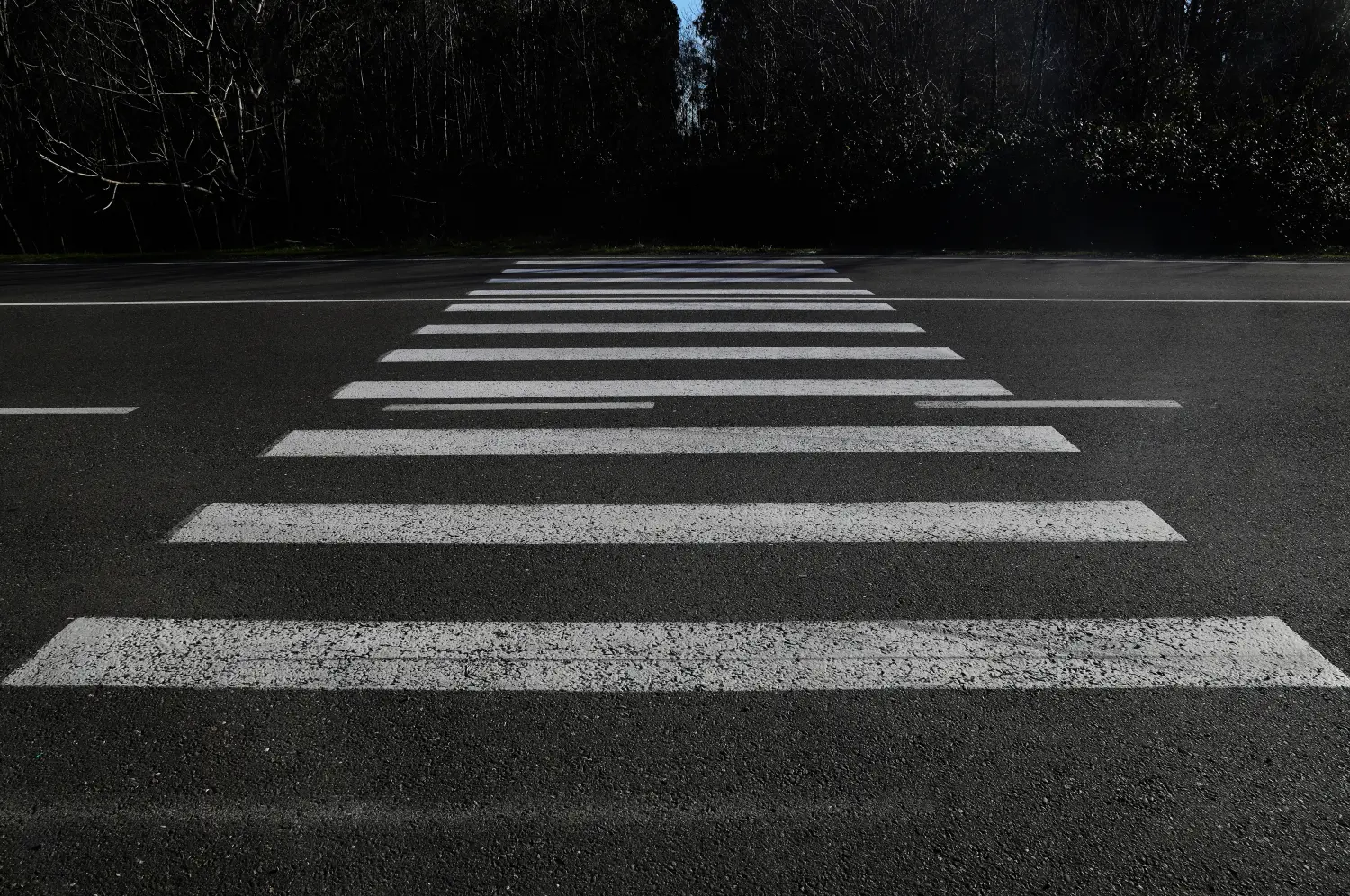 Zebrastreifen auf der Straße für die Sicherheit von Fußgängern beim Überqueren der Straße, Fußgängerüberweg auf einer reparierten Asphaltstraße